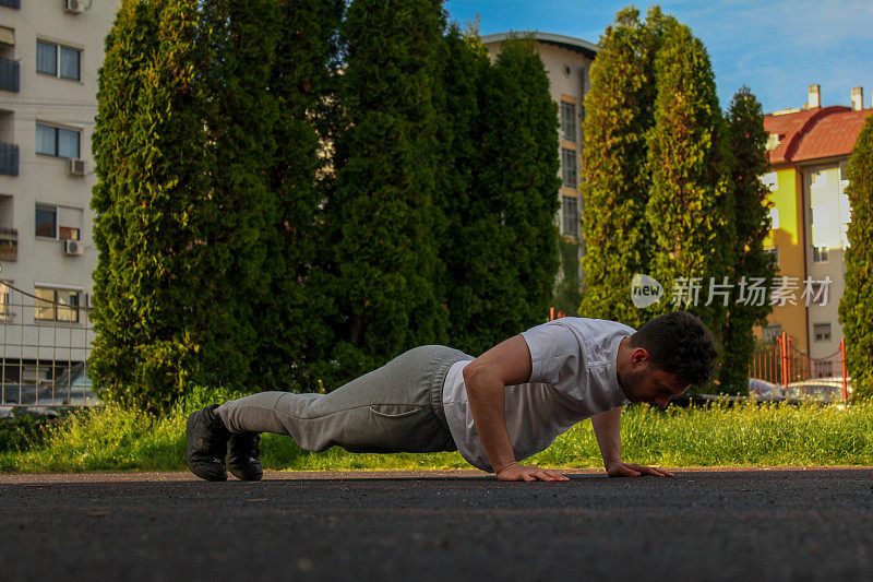 A white man doing a pushup in a public park